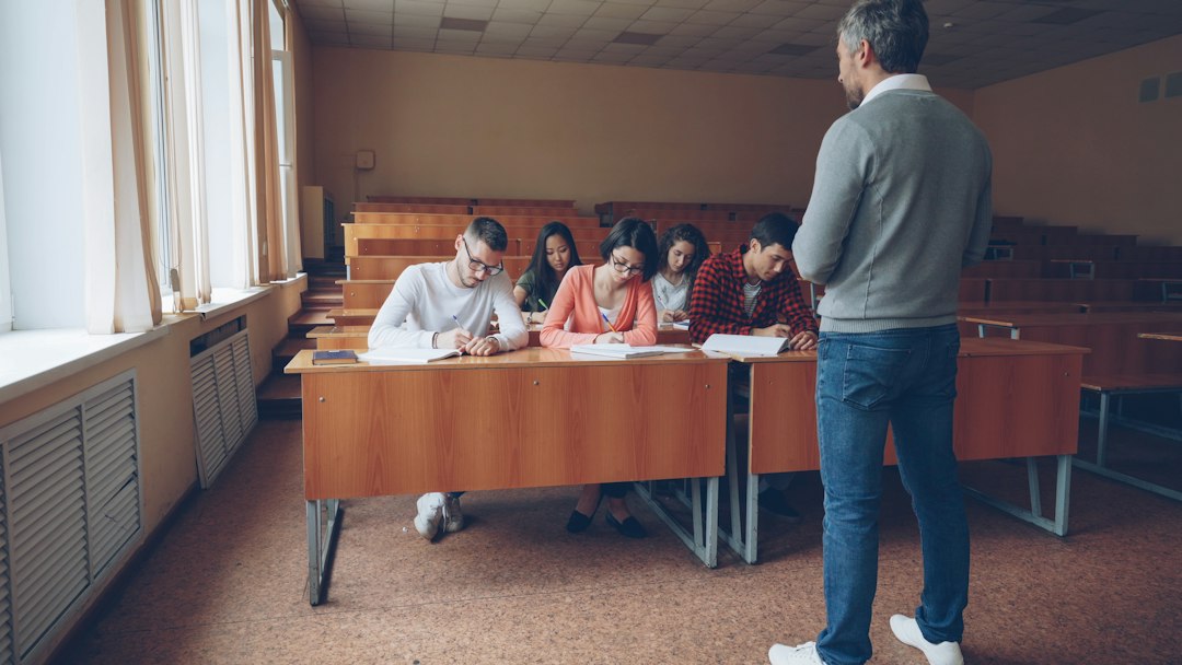 Students writing an assessment in a university lecture hall, illustrating how program outcomes are measured against the curriculum map
