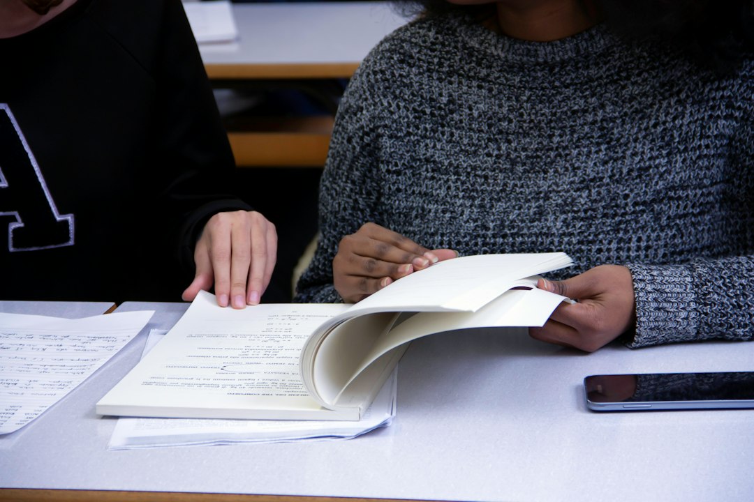 Two faculty members reviewing course materials and assessment papers at a table