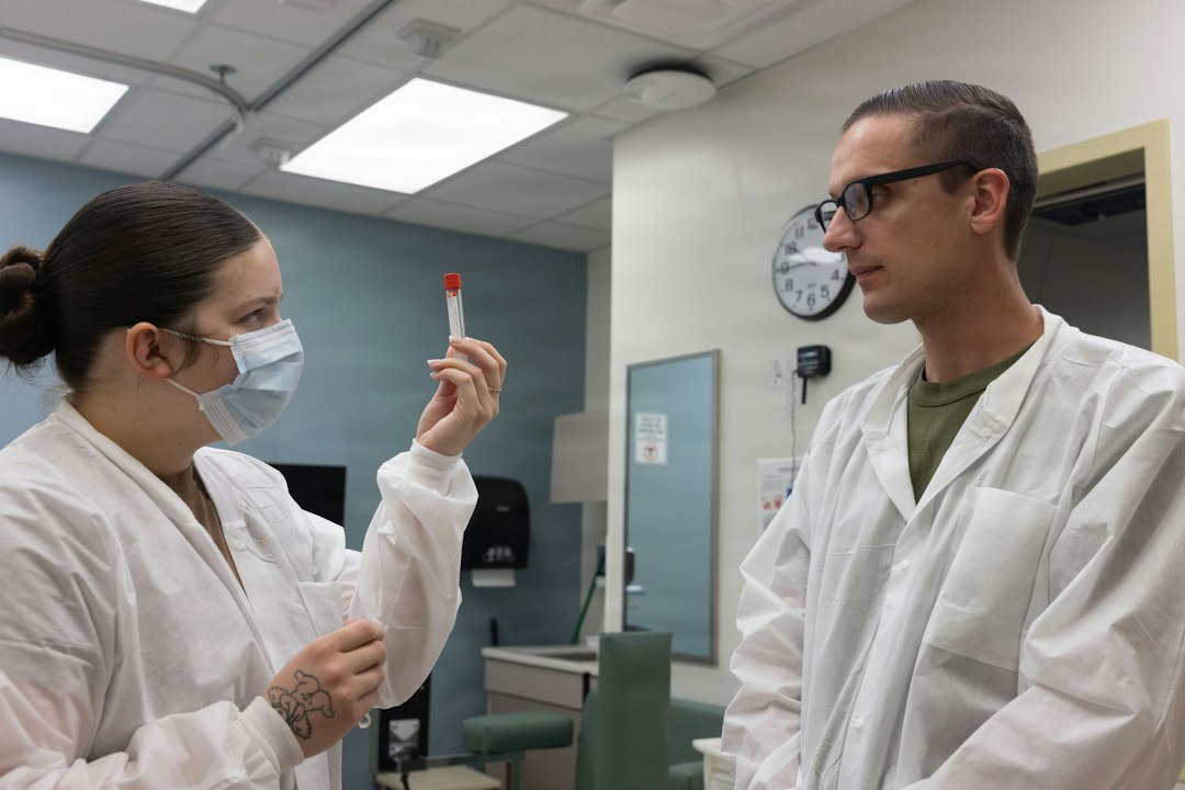 A preceptor holds up a blood-collection vial and explains it to a student during a clinical training session.