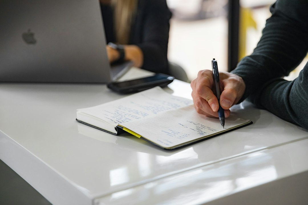 Coordinator writing the self-study narrative by hand at a desk