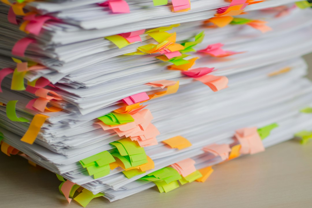 A stack of printed documents marked with colourful sticky tabs, ready to be filed and referenced